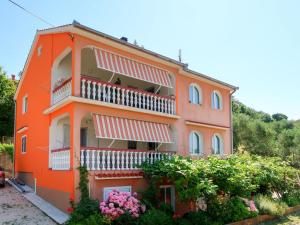 un bâtiment orange avec des balcons et des fleurs dans l'établissement Apartment Dorka - RAB303 by Interhome, à Rab