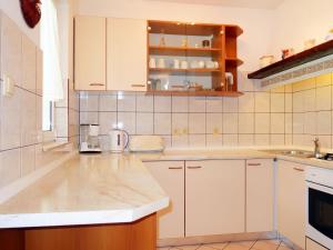 una cucina con armadi bianchi e piano di lavoro di Apartment Dorka - RAB303 by Interhome a Rab