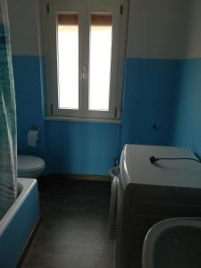 La salle de bains est pourvue de murs bleus, de toilettes et d'un lavabo. dans l'établissement Lilla, à Bellagio