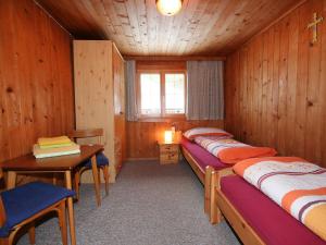 Zimmer mit 2 Betten, einem Tisch und einem Schreibtisch in der Unterkunft Apartment Mangeng-2 by Interhome in Bartholomäberg
