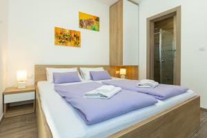 1 dormitorio con 1 cama grande con sábanas moradas en Apartments Maris, en Sveti Filip i Jakov