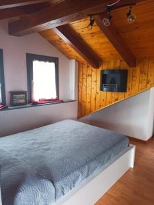 ein Schlafzimmer mit einem Bett und einem TV an der Wand in der Unterkunft Maison Bellevue - locazione turistica breve in Aosta