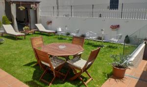 una mesa de madera y sillas en un patio con césped en PortoSantiago, en Portomarín