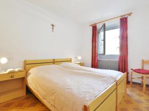 a bedroom with a bed and a window at Apartment Maura-2 by Interhome in Pozza di Fassa