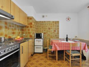 eine Küche mit einem Tisch, einem Herd und einem Tisch mit Stühlen in der Unterkunft Apartment Maura-2 by Interhome in Pozza di Fassa