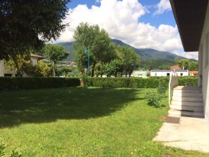 une cour avec une pelouse verdoyante et des montagnes en arrière-plan dans l'établissement Holiday Home Villetta ai Pini-1 by Interhome, à Calceranica al Lago