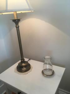 una lámpara y un frasco de cristal sobre una mesa blanca en La Belle aux Berges, en Saint-Denis-sur-Richelieu