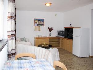 ein Wohnzimmer mit einem weißen Kühlschrank und eine Küche in der Unterkunft Apartment Martinelli by Interhome in Calceranica al Lago