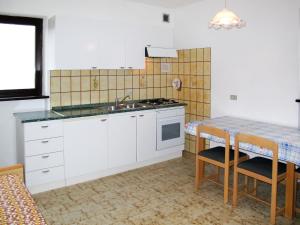 カルチェラーニカ・アル・ラーゴにあるApartment Martinelli by Interhomeの白いキャビネット、シンク、テーブル付きのキッチンが備わります。