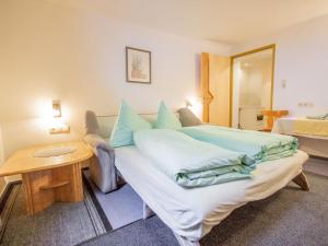 a bedroom with a bed with blue pillows and a table at Apartment Christian by Interhome in Pettneu am Arlberg