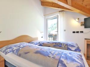 a bedroom with a bed with a blue comforter and a window at Apartment Cecilia-4 by Interhome in Campitello