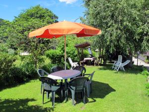einen Tisch und Stühle mit einem Regenschirm auf dem Rasen in der Unterkunft Apartment Deval-2 by Interhome in Calceranica al Lago