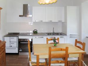 een keuken met witte kasten en een houten tafel met stoelen bij Holiday Home Casa al Mulino by Interhome in Calceranica al Lago