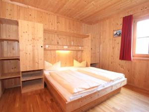 ein Schlafzimmer mit einem Bett in einem Holzzimmer in der Unterkunft Holiday Home Schwendau-1 by Interhome in Hippach