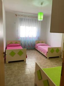 a bedroom with two beds and a green rug at Agaraj apartament in Orikum