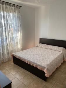 a bedroom with a large bed with curtains at Agaraj apartament in Orikum