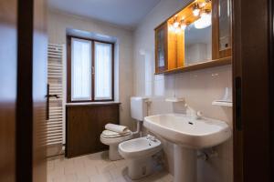 uma casa de banho branca com um lavatório e um WC em La Marmote Albergo Diffuso di Paluzza Cleve em Paluzza