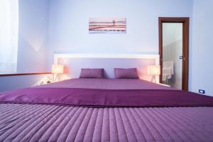 トラーパニにあるB&B Trapani Inのベッドルーム(紫色のベッド1台、ランプ2つ付)