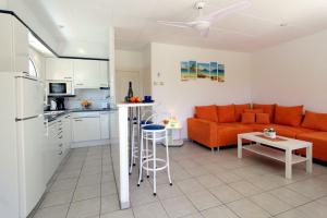 ein Wohnzimmer mit einem orangenen Sofa und einer Küche in der Unterkunft LEON INMO Apartment Celine - 10413 in Empuriabrava