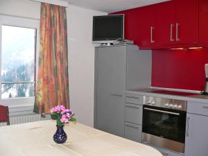 una cucina con armadi rossi e un tavolo con un vaso di fiori di Apartment Elsa by Interhome a Blons