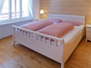 Holiday Home Chalet Ahornen by Interhome في جريندلفالد: سرير أبيض مع وسائد وردية عليه في غرفة