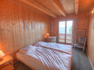 ein Schlafzimmer mit einem Bett, einem Stuhl und einem Fenster in der Unterkunft Chalet Arpille by Interhome in Anzère