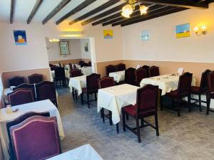a dining room with white tables and red chairs at Seawold Guest House in St. Brelade