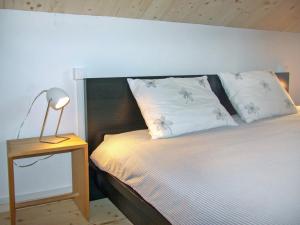 a bed with two pillows and a lamp on a table at Chalet Börtji by Interhome in Furna