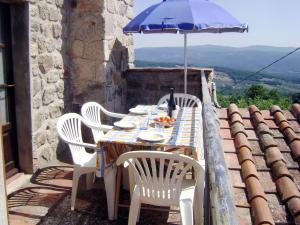 uma mesa com cadeiras e um guarda-sol no telhado em Apartment Rosa - Borgo la Civitella by Interhome em Roccastrada