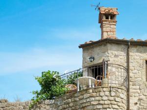 um edifício de pedra com uma chaminé e uma varanda em Apartment Torretta - Borgo la Civitella by Interhome em Roccastrada