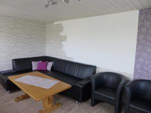 ein Wohnzimmer mit einem schwarzen Ledersofa und 2 Stühlen in der Unterkunft Holiday Home Martin by Interhome in Wald