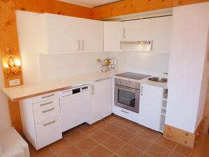 a small kitchen with white cabinets and a sink at Apartment Le Bristol C54 by Interhome in Villars-sur-Ollon +20 photos