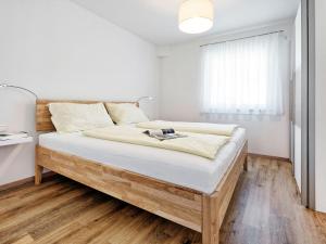 een slaapkamer met een bed met witte muren en houten vloeren bij Apartment Deutschbauer - FAK100 by Interhome in Egg am Faaker See