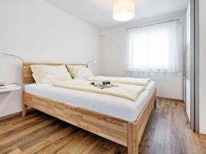 a bedroom with a bed with white walls and wooden floors at Apartment Deutschbauer - FAK100 by Interhome in Egg am Faaker See