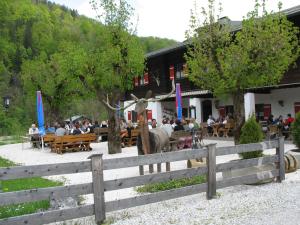 a group of people sitting at tables in front of a building at Wirtshaus und Pension Hocheck in Ramsau