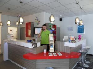 a man talking on a cell phone at a counter at ibis Styles Grenoble Centre Gare in Grenoble