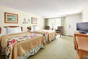 a hotel room with two beds and a flat screen tv at Ogunquit The Milestone Inn in Ogunquit