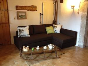 uma sala de estar com um sofá preto e uma mesa de centro em Apartment Les Grangettes by Interhome em Auberson