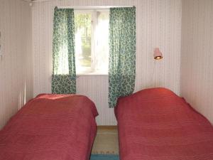 1 Schlafzimmer mit 2 Betten und einem Fenster mit Vorhängen in der Unterkunft Chalet Älgnäs - HSL040 by Interhome in Stråtjära
