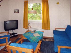 ein Wohnzimmer mit blauen Stühlen, einem Tisch und einem TV in der Unterkunft Chalet Älgnäs - HSL040 by Interhome in Stråtjära