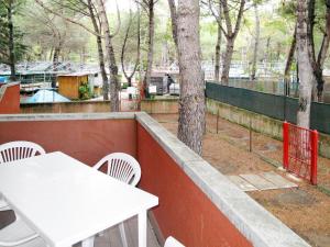 einen weißen Tisch und Stühle auf einem Balkon mit einem Baum in der Unterkunft Apartment Campeggio del Forte-1 by Interhome in Marina di Bibbona