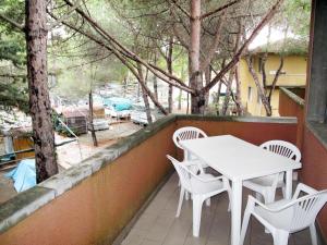 マリーナ・ディ・ビッボーナにあるApartment Campeggio del Forte-1 by Interhomeの木々が植えられたバルコニーに白いテーブルと椅子