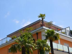 a building with a balcony and palm trees at Apartment Residenza Corallo-10 by Interhome in Ascona