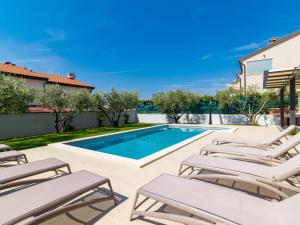 a swimming pool with lounge chairs next to a villa at Holiday Home Jadranka by Interhome in Novigrad Istria