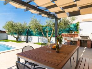 a wooden table and chairs on a patio with a pool at Holiday Home Jadranka by Interhome in Novigrad Istria