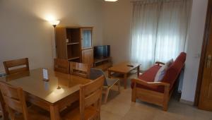een woonkamer met een tafel en stoelen en een televisie bij Apartamentos entreRíos in Cazorla