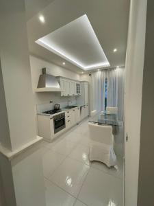 a kitchen with white cabinets and a glass table at Minori Palace De Luxe Apartment in Minori