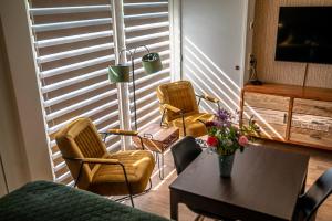 a living room with chairs and a table and a tv at B&B de Scherpenhof, landelijk gelegen met optie jacuzzi in Leur +40 photos