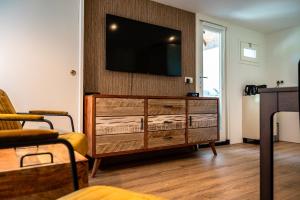a living room with a television on a wall at B&B de Scherpenhof, landelijk gelegen met optie jacuzzi in Leur