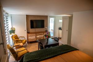 a living room with a bed a table and a television at B&B de Scherpenhof, landelijk gelegen met optie jacuzzi in Leur